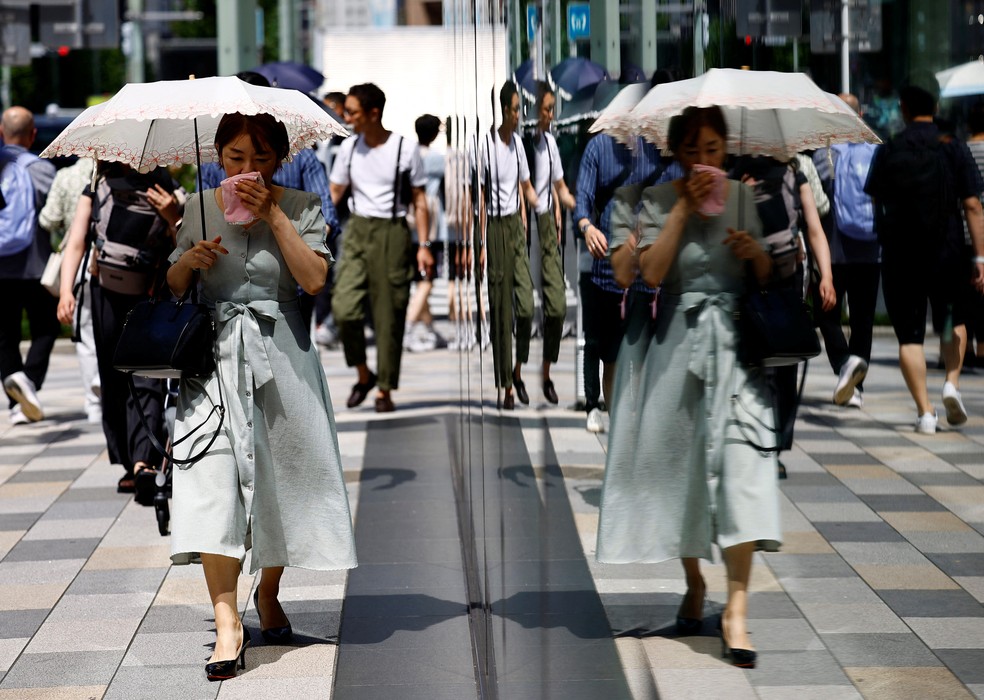 Mulher caminha com guarda-sol e lenço durante onda de calor em Tóquio, em 9 de julho de 2024. — Foto: Issei Kato/ Reuters